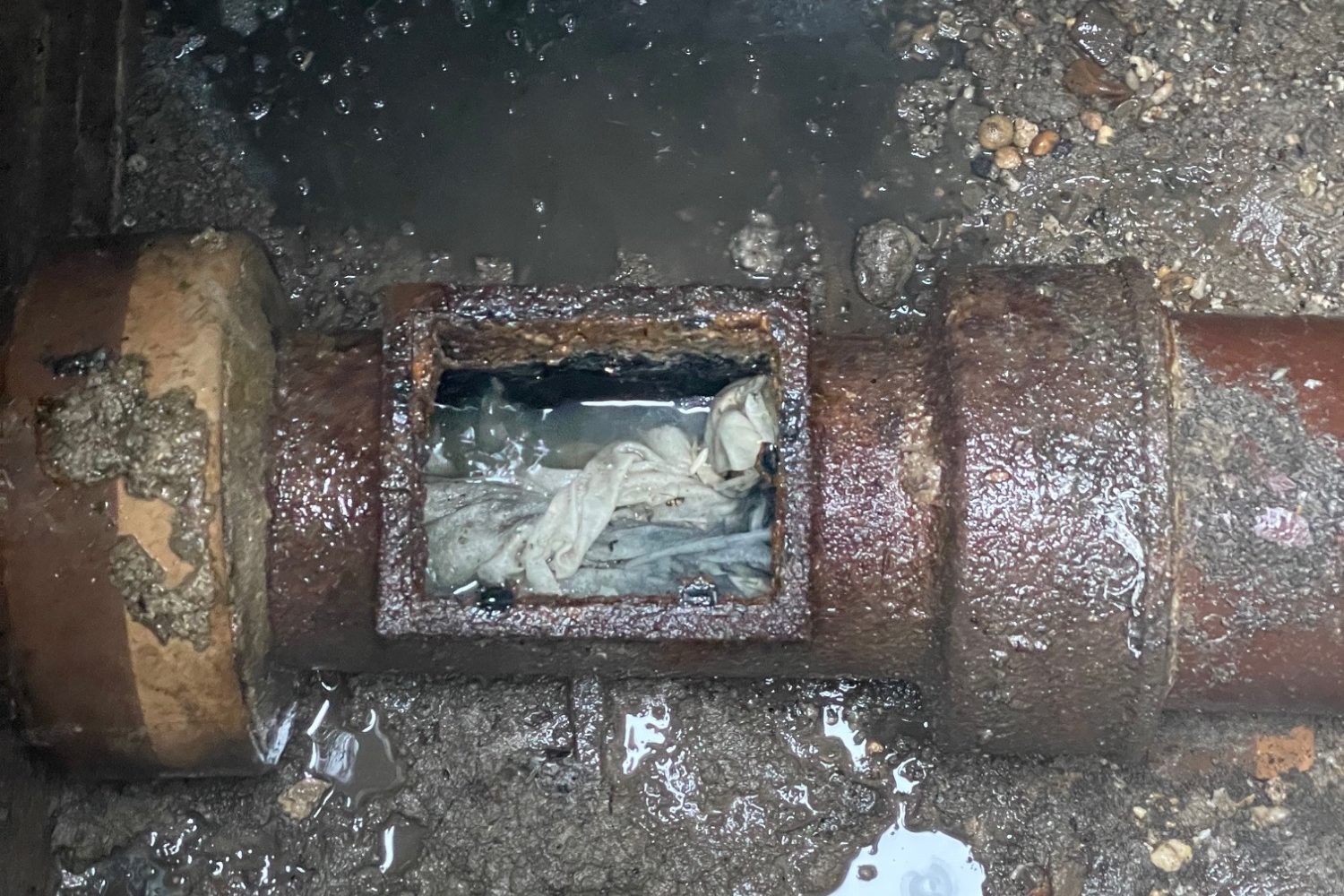 Verstopfung Rostige Rohrleitung mit einer offenen Stelle, die Ablagerungen zeigt.